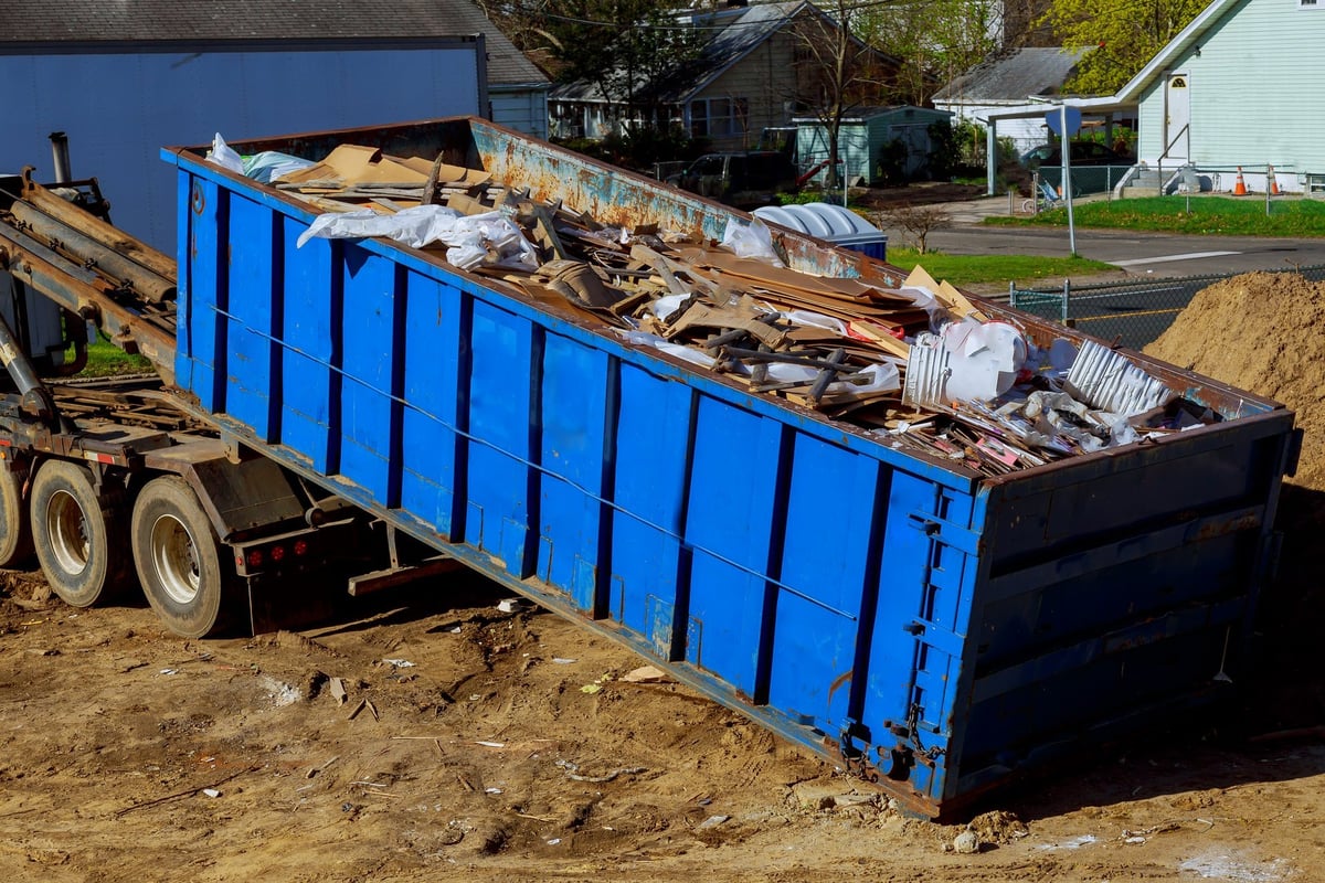 Truck loading a skip container of waste